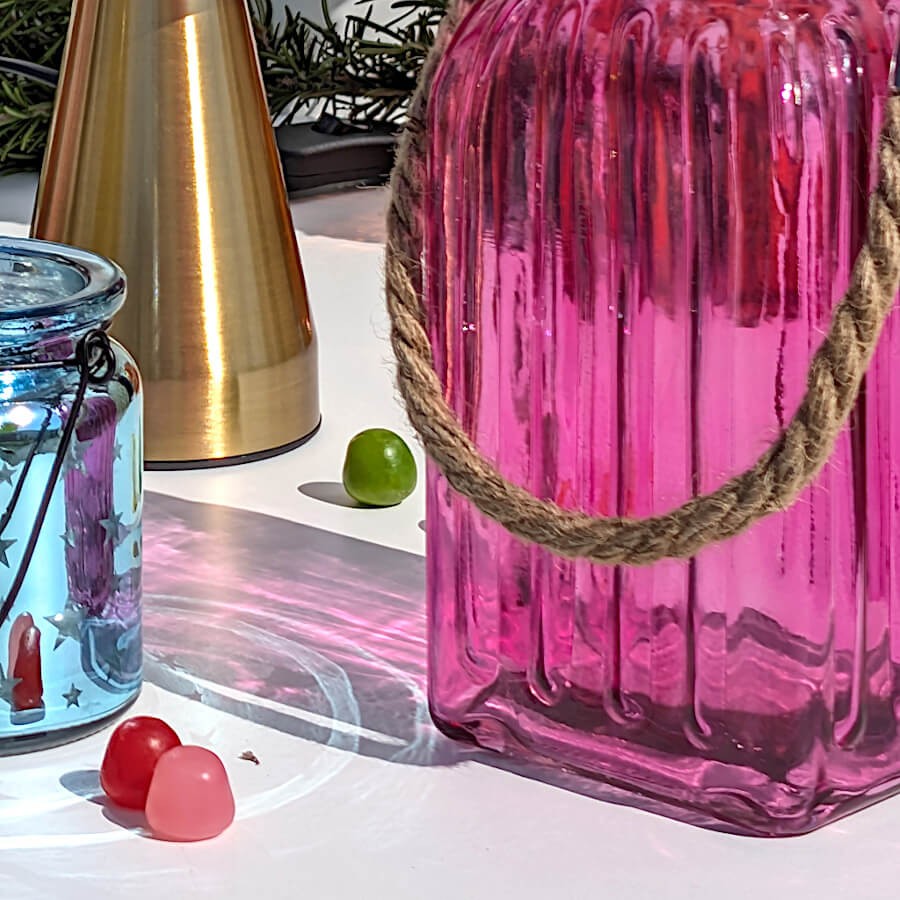 Reflets solaires : Les ombres colorées et texturées de la lanterne rose fuchsia projetées sur une surface blanche.