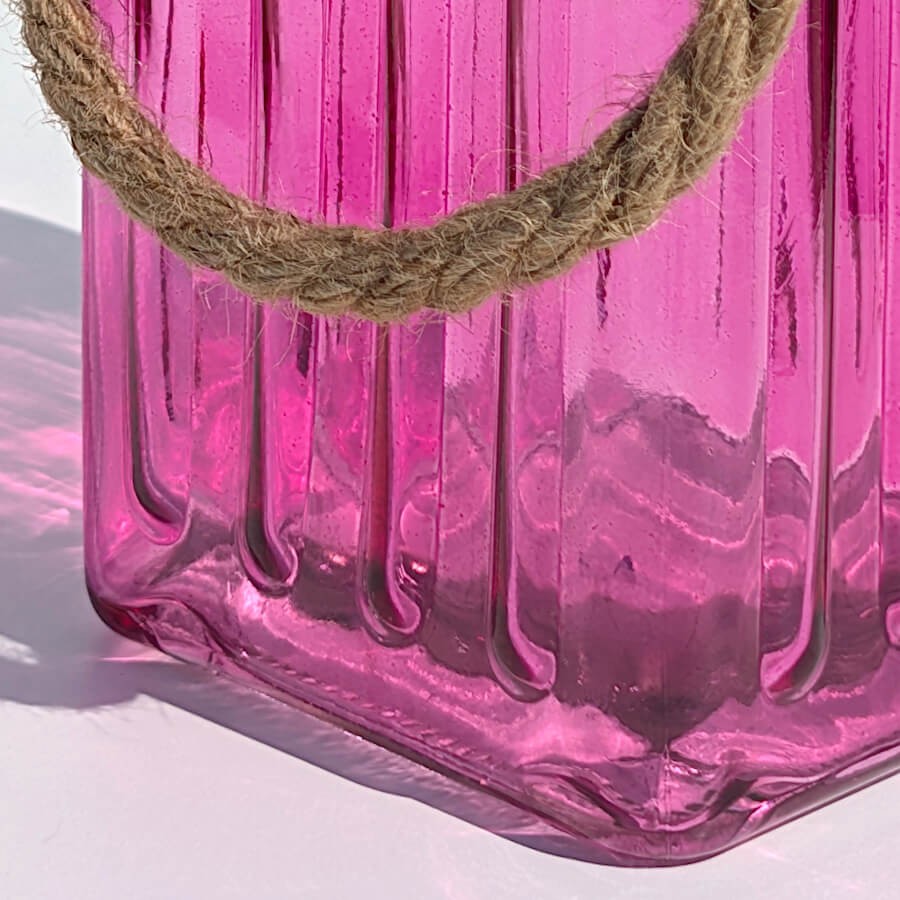 Zoom relief fuchsia : Détail rapproché sur les ondulations géométriques gravées dans le verre teinté rose magenta.