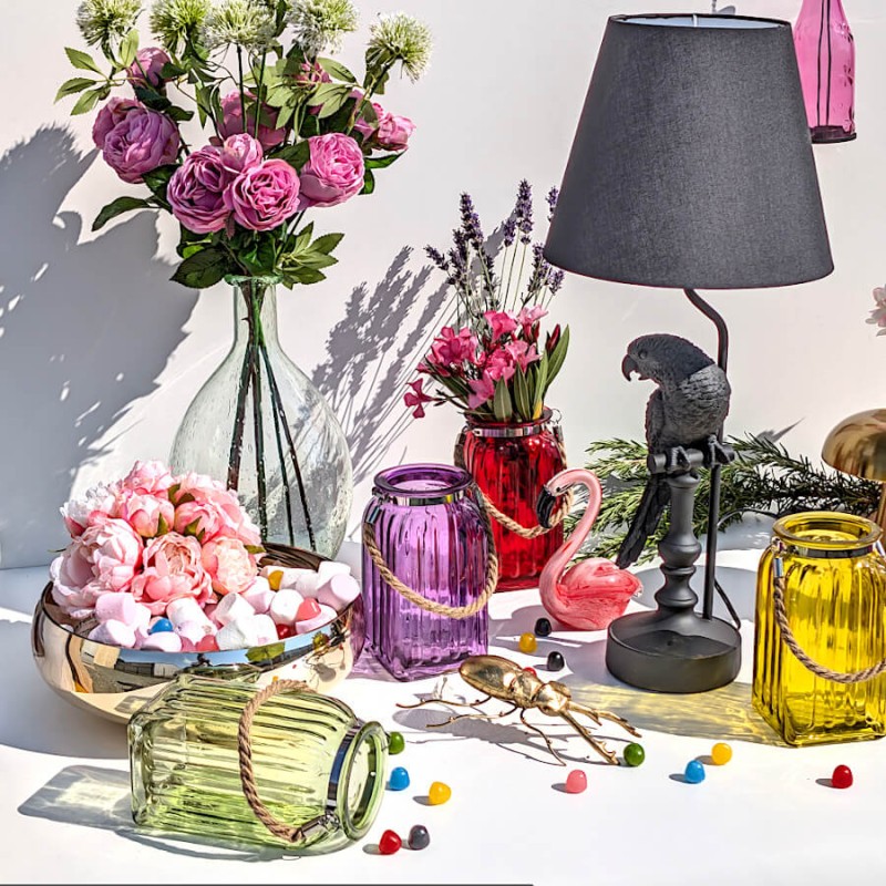 Composition décorative sur table basse avec bouquets de fleurs, lampes et lanternes colorées.