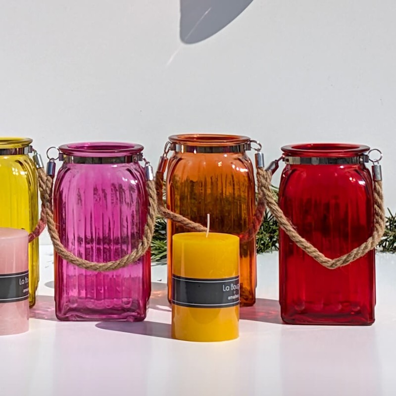 Alignement de bougies : Lanternes colorées alignées devant une bougie pilier jaune hydromel, mettant en valeur le modèle rouge.