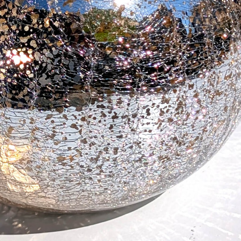 Très gros plan sur la texture mouchetée, argentée et scintillante de la paroi en verre craquelé.