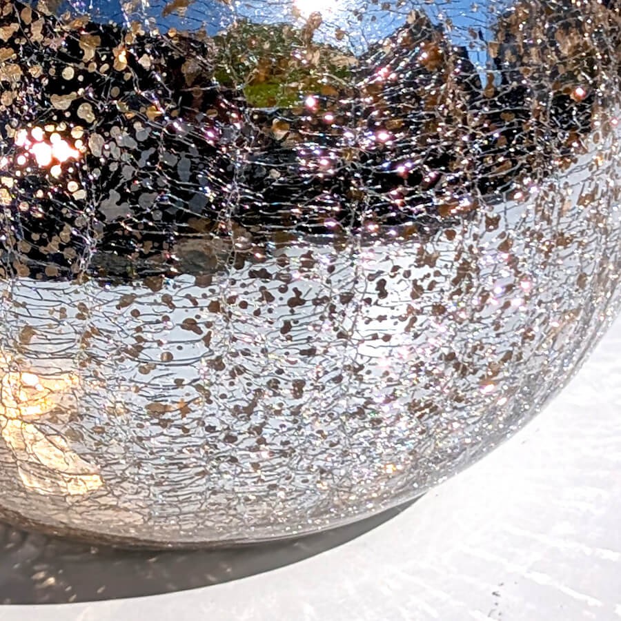 Très gros plan sur la texture mouchetée, argentée et scintillante de la paroi en verre craquelé.