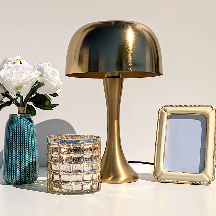 Photophore en verre gaufré mercurisé mis en scène sur une console blanche à côté de la lampe rétro chic dorée.