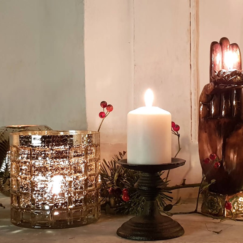 Ambiance de Noël chaleureuse avec le photophore en verre gaufré illuminé près d'une bougie pilier sur un bougeoir noir.