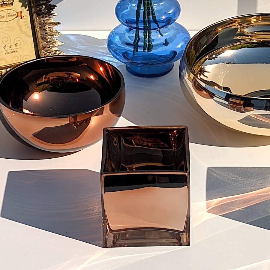 Composition de table mettant en relief le photophore et les deux coupelles en verre doré et cuivré  avec le vase bleu azur.