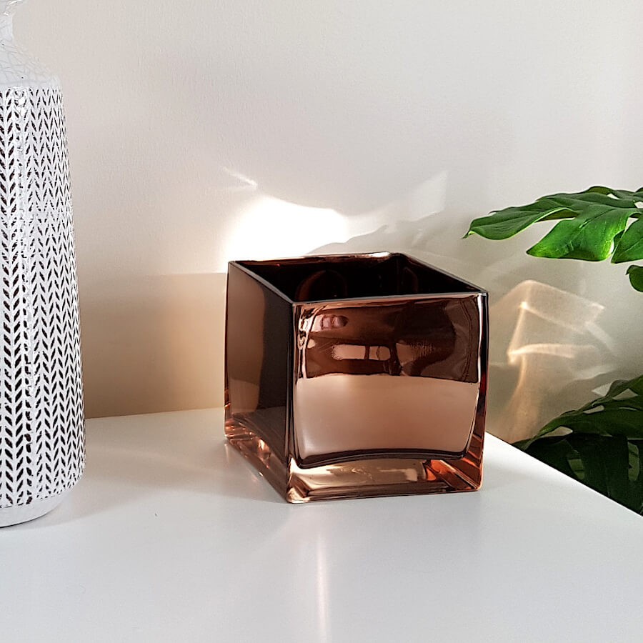Le photophore cuivré mis en valeur sur un meuble blanc épuré à côté d'un grand vase blanc de notre collection.