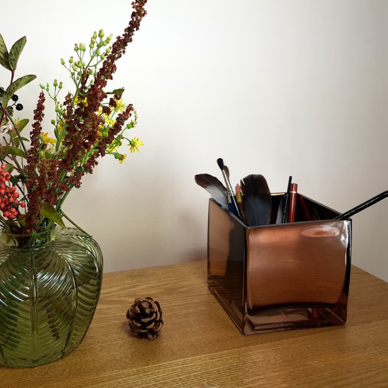 Utilisation détournée originale du photophore cuivré comme pot à pinceaux sur un bureau en bois.