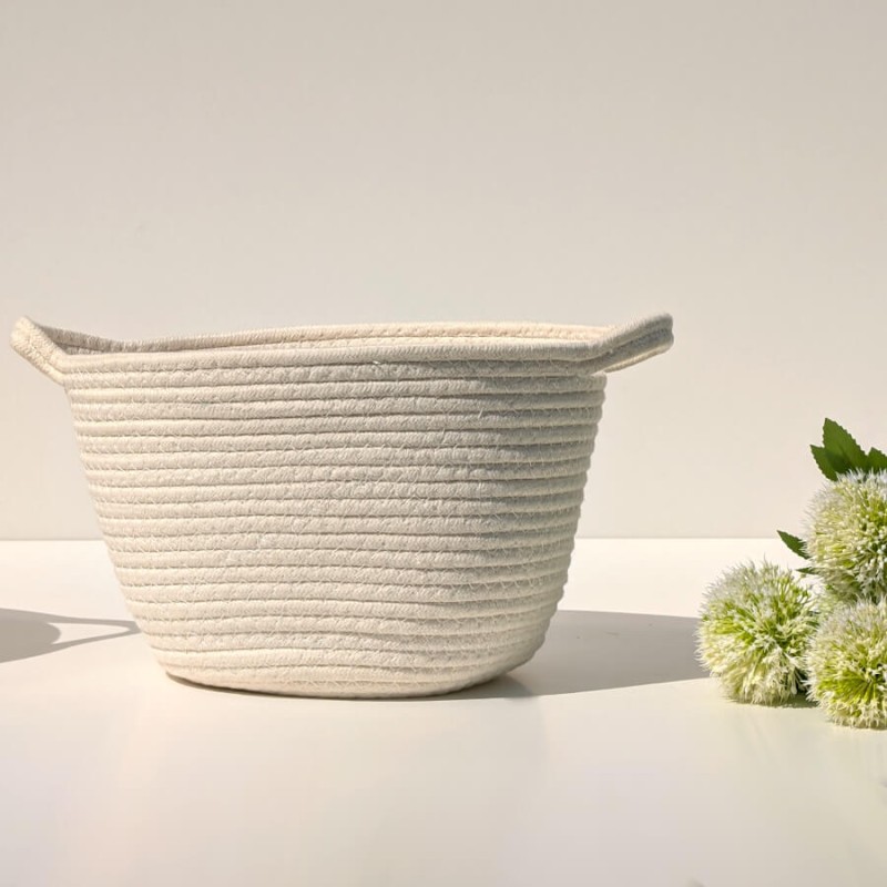 Vue de face épurée : Panier de rangement souple blanc cassé posé sur un meuble blanc lumineux.