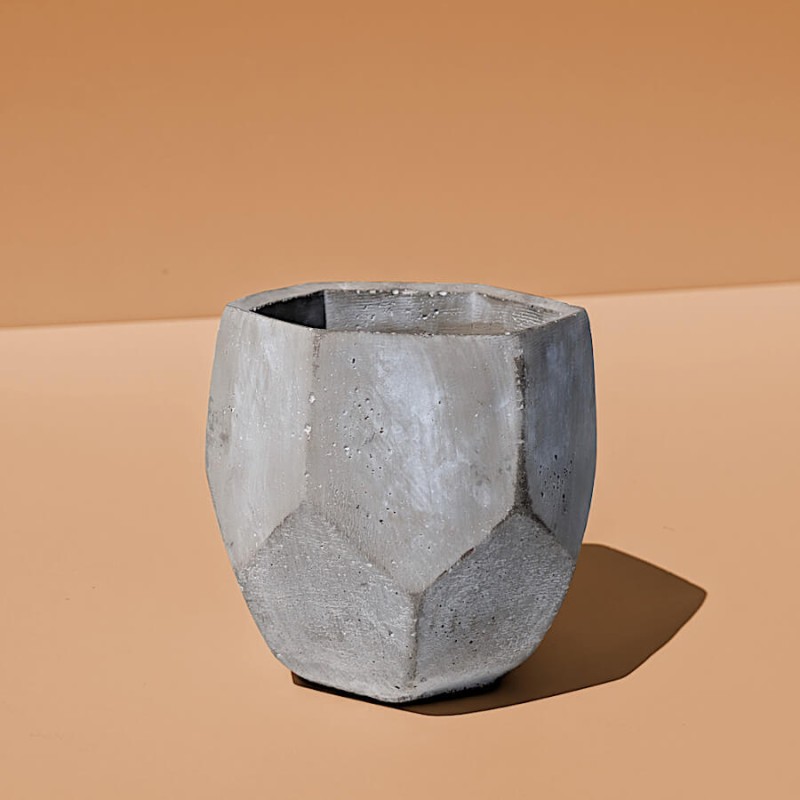 Présentation isolée du pot en ciment facetté mettant en relief sa forme hexagonale et ses découpes angulaires.