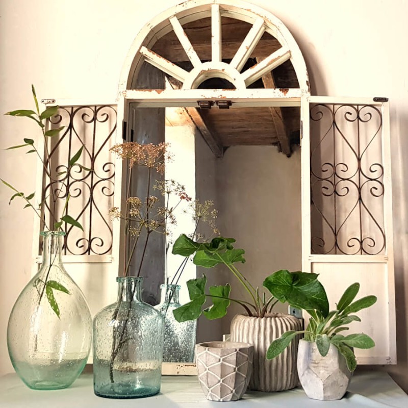 Présentation esprit verrière avec de grands vases bouteilles , le miroir fenêtre crème et les pots en ciment.