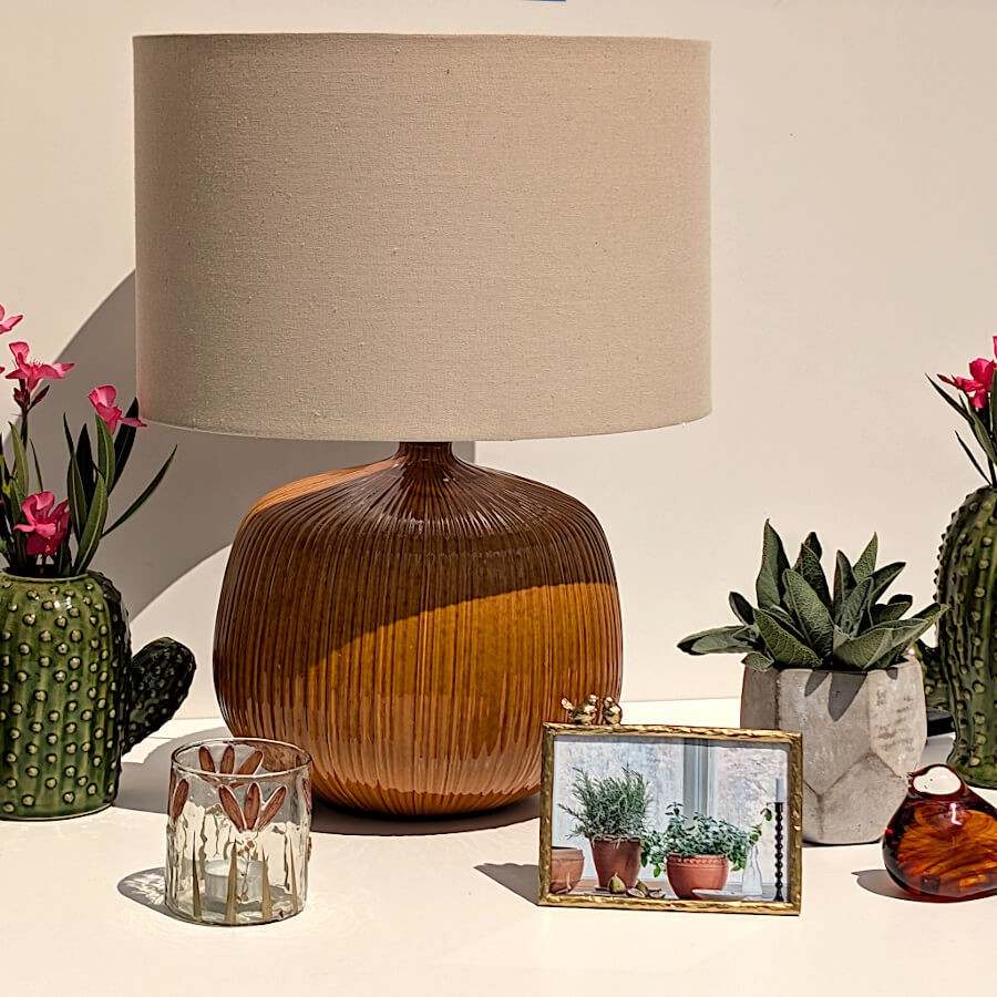 Décoration d'intérieur épurée associant un cache-pot cactus vert, la lampe ocre et le petit pot géométrique facetté.