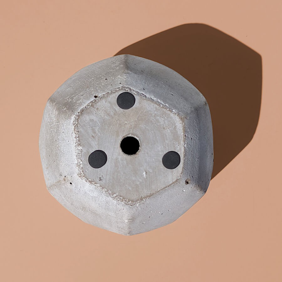 Vue de dessous montrant la base stable, les trois patins feutres de protection et le trou de drainage central.