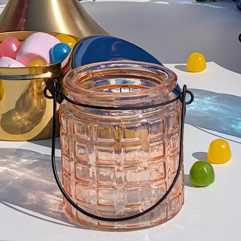 Photophore en verre teinté teinte pèche/saumon éclairé par le soleil.