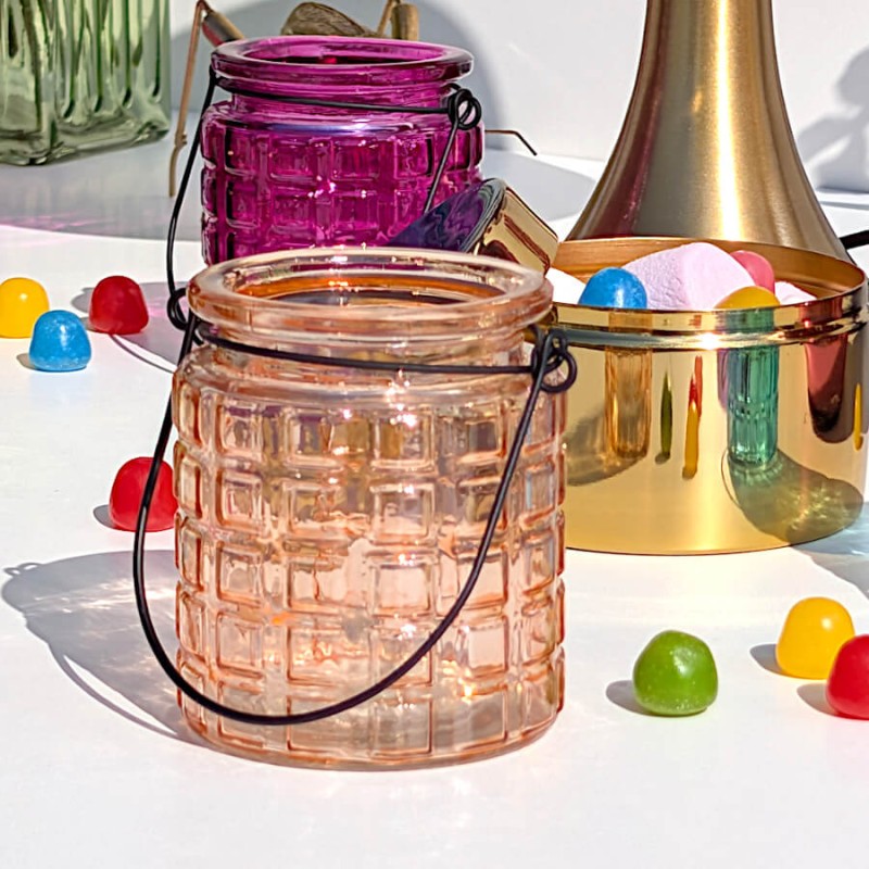 Photophore orange-saumon sur une table de fête avec bonbons multicolores.