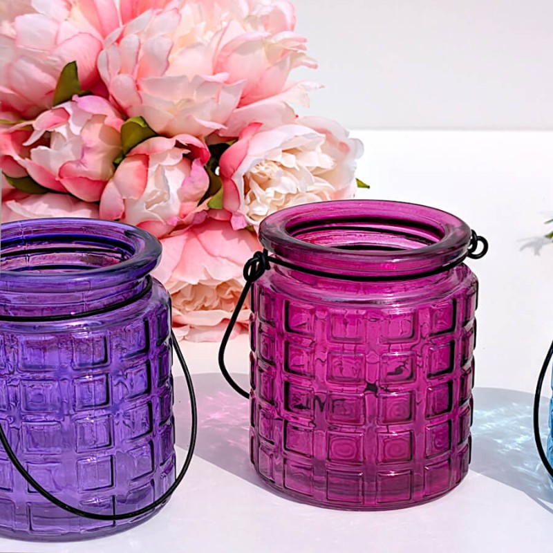 Duo de photophores en verre teinté fuchsia et violet à côté de pivoines artificielles Deco Delight.