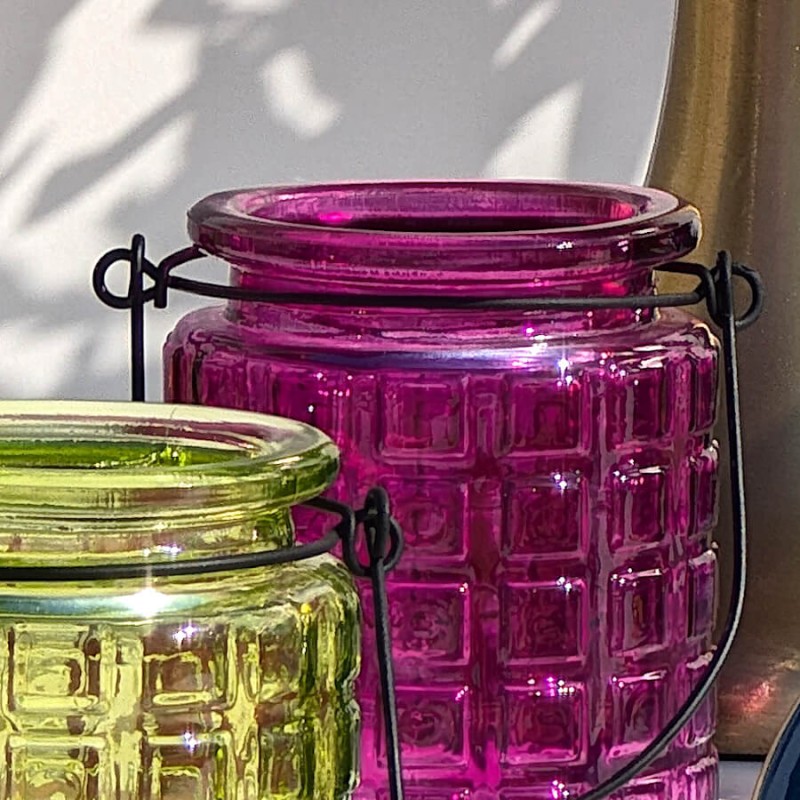 Gros plan sur le col et l'anse noire du photophore fuchsia à côté d'un modèle vert.