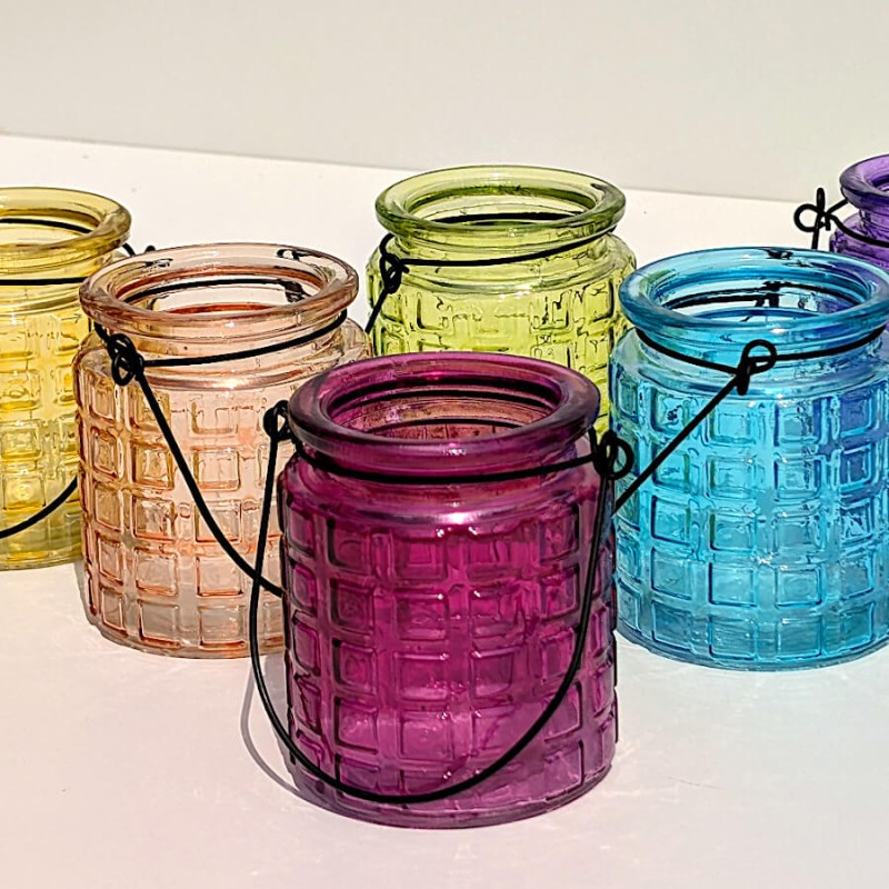 Collection de petits photophores en verre teinté dans un camaïeu de couleurs estivales.
