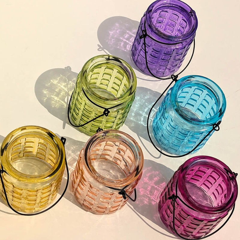 Ensemble de photophores en verre coloré, disposés en triangle dans une ambiance estivale.