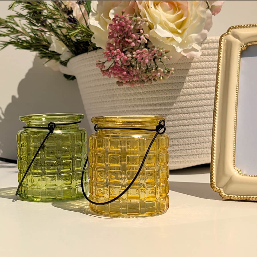 Duo de photophores vert et jaune sur une table d'été.