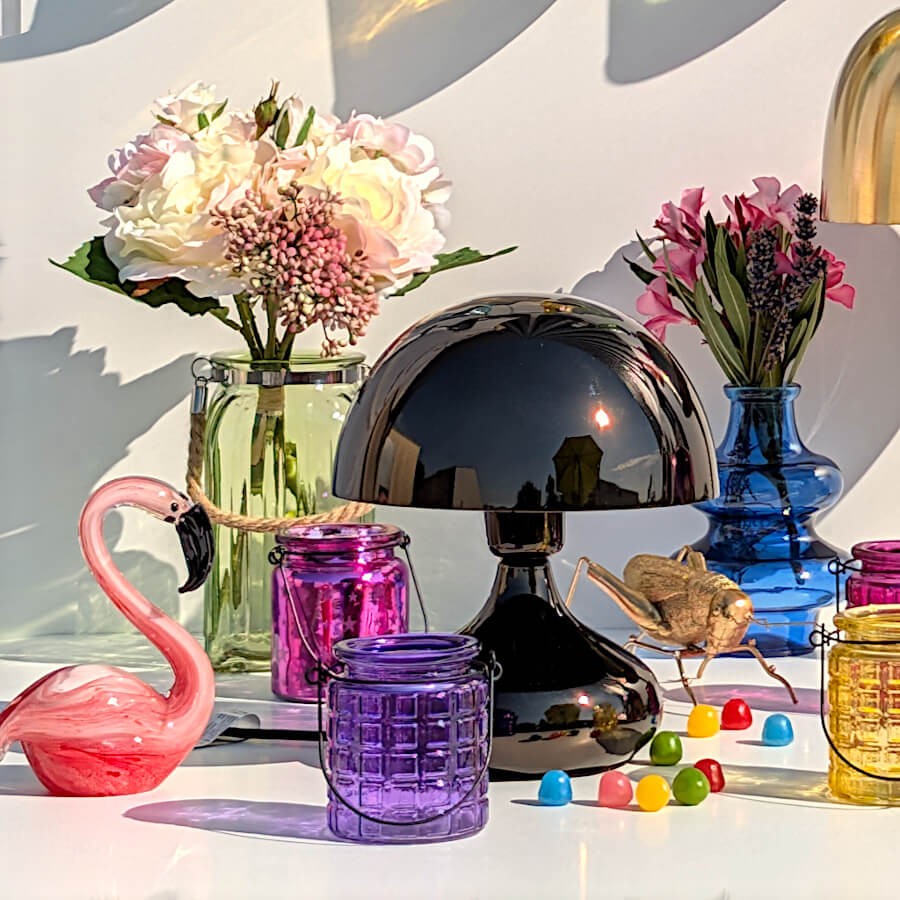 Décoration d'un meuble avec le photophore violet en verre, la lampe champignon noire et un flamant rose.