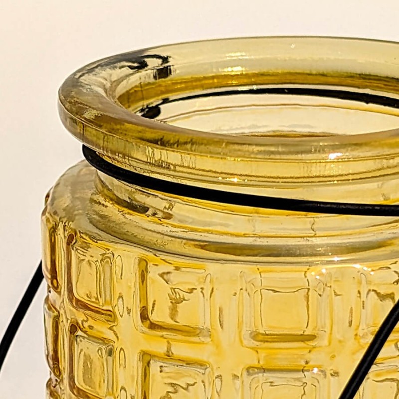 Zoom sur le bord et le motif gaufré du photophore jaune en verre.