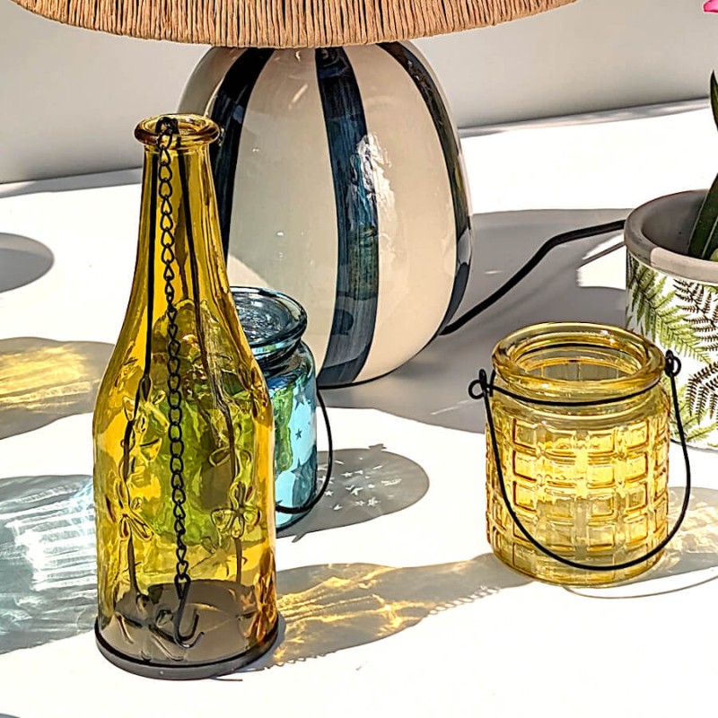 Scénographie estivale associant bouteille décorative en verre et photophore jaune en verre gaufré.
