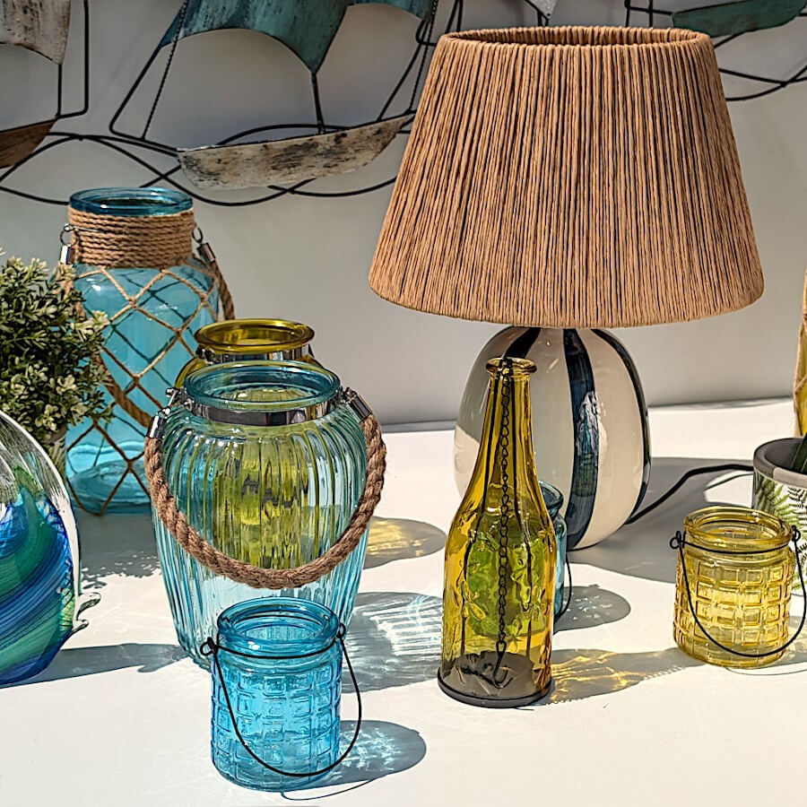 Décoration de terrasse jaune et bleue avec lampe à poser striée et photophore jaune en verre.