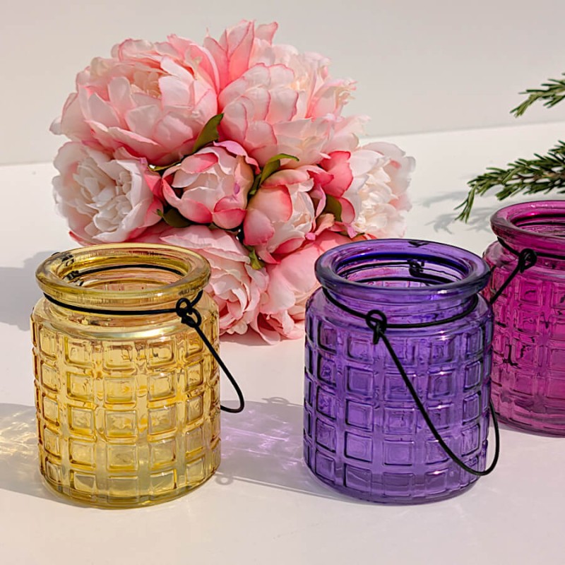 Duo de photophores en verre gaaufré jaune et violet devant un bouquet de pivoines artificielles, collection Deco-Delight.