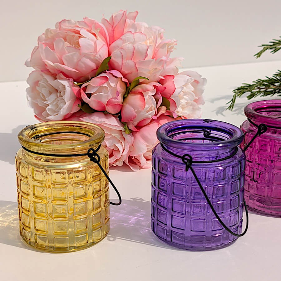 Duo de photophores en verre gaaufré jaune et violet devant un bouquet de pivoines artificielles, collection Deco-Delight.