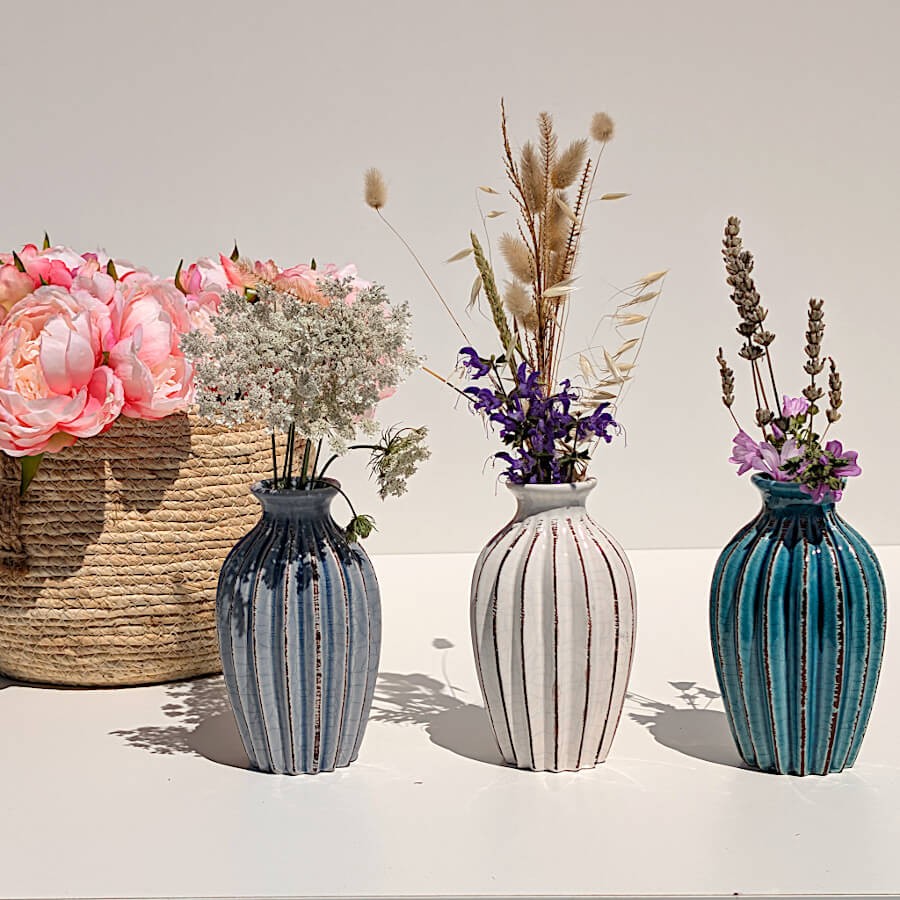 Les trois teintes de vases plissés (gris, blanc et turquoise) garnis de fleurs.