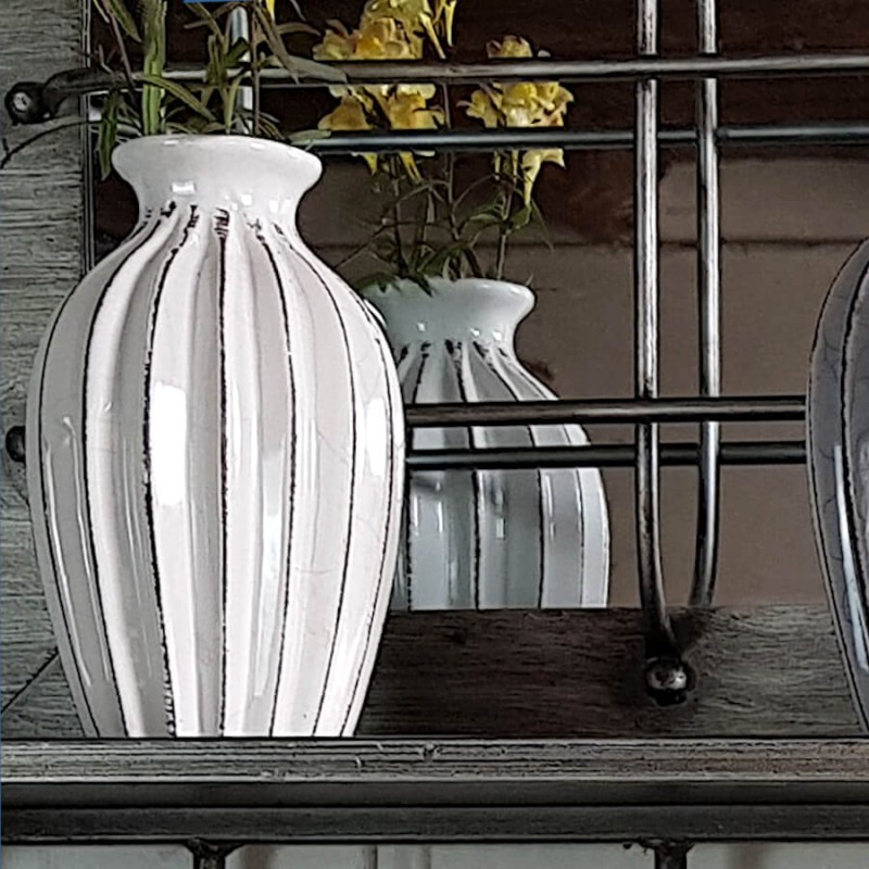 Le vase plissé blanc mis en valeur sur l'étagère en métal du miroir à 5 patères.