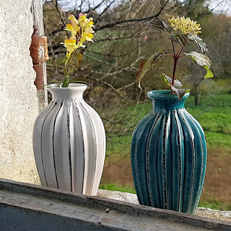 Duo de vases plissés (blanc et turquoise) avec fleurs de saison en extérieur.