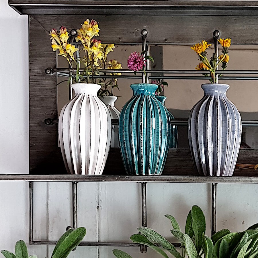 Les trois vases plissés disposés en ligne et agrémentés de fleurs.