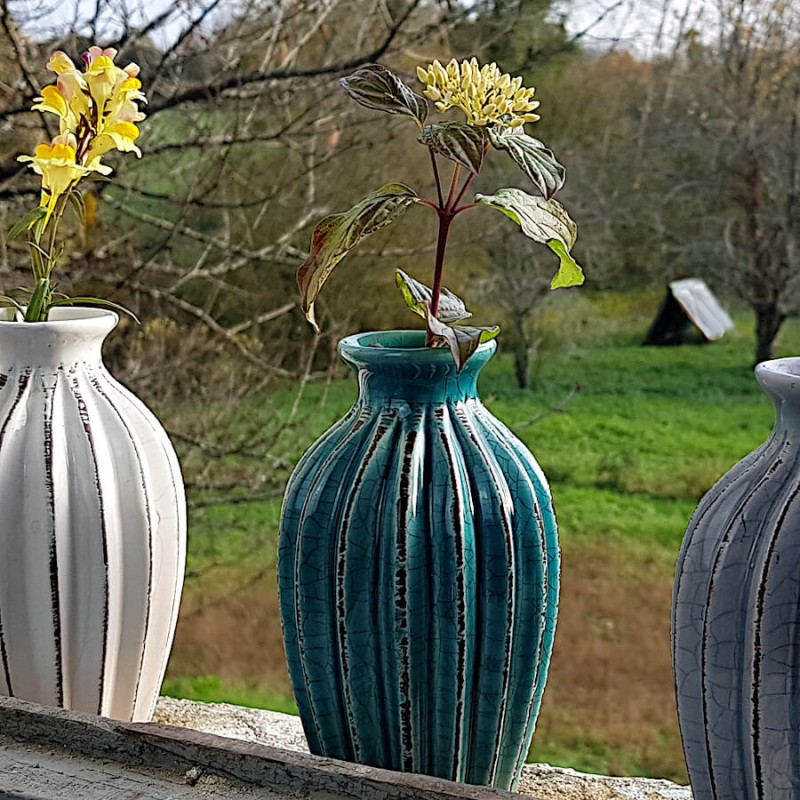 Duo de vases plissés (blanc et turquoise) présentés sur un rebord de fenêtre.