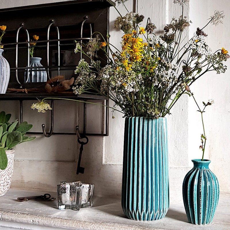 Le petit vase turquoise aux côtés d'un grand vase origami et d'un photophore Étoile en verre.