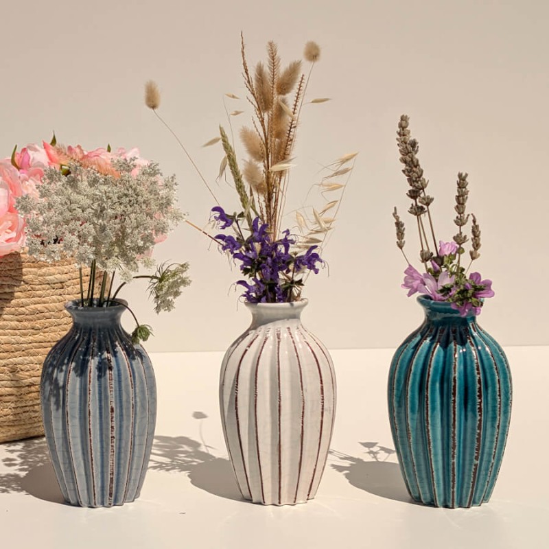 Trio de vases plissés (gris, blanc, turquoise) garnis de brins séchés.