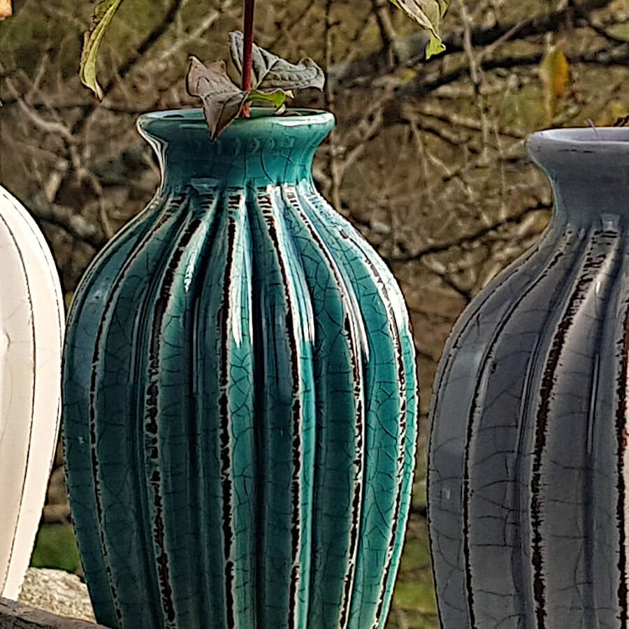 Gros plan sur le relief strié et la patine émaillée du vase turquoise.