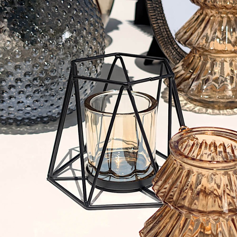 Le photophore hexagonal noir présenté à côté d'un bougeoir sapin en verre ambré.