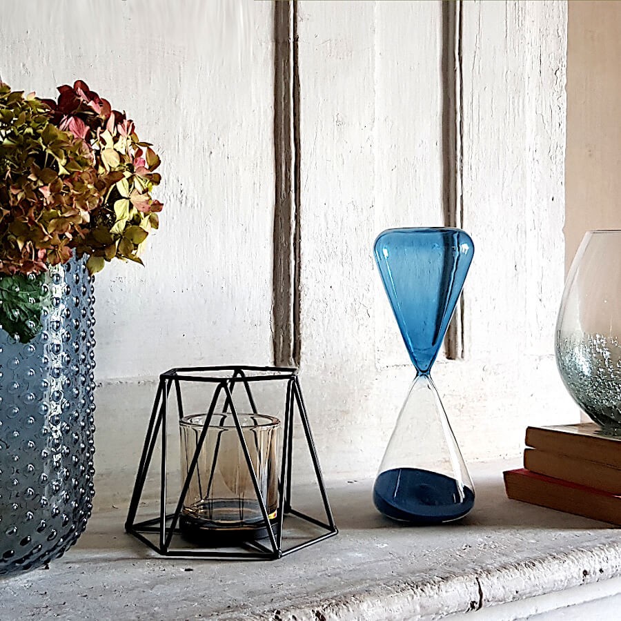 Décoration d'intérieur chaleureuse avec le photophore filaire noir, un sablier bleu et un grand vase texturé.