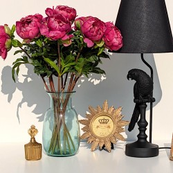 Cadre photo rond motif soleil doré posé à côté d'un vase en verre bleu et d'une boîte ex-voto.