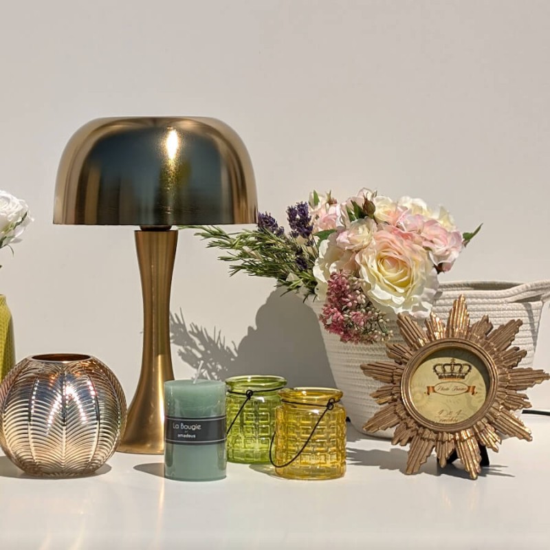 Ambiance dorée et lumineuse avec le cadre soleil, une lampe champignon dorée et des photophores et bougie.