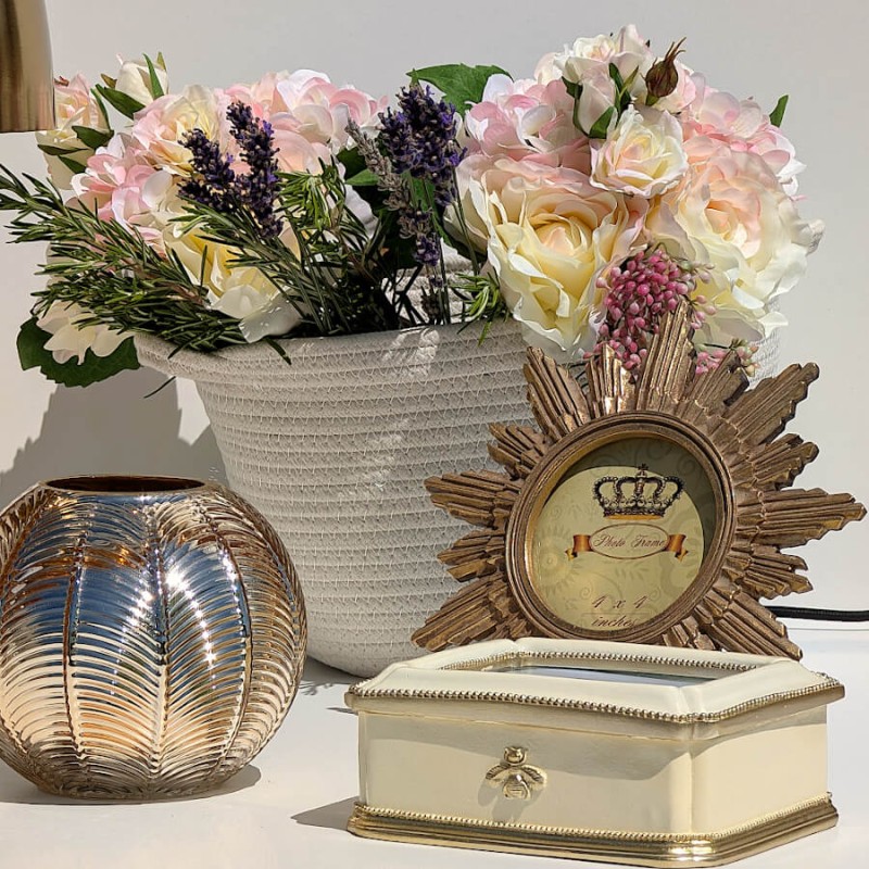 Cadre rond soleil présenté sur un coffre vintage avec une boîte à bijoux crème et un bouquet champêtre.