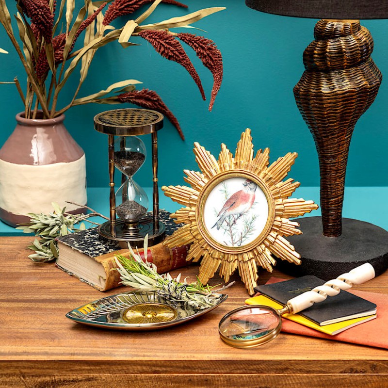 Décoration de bureau d'inspiration cabinet de curiosités avec le cadre soleil doré et un sablier.
