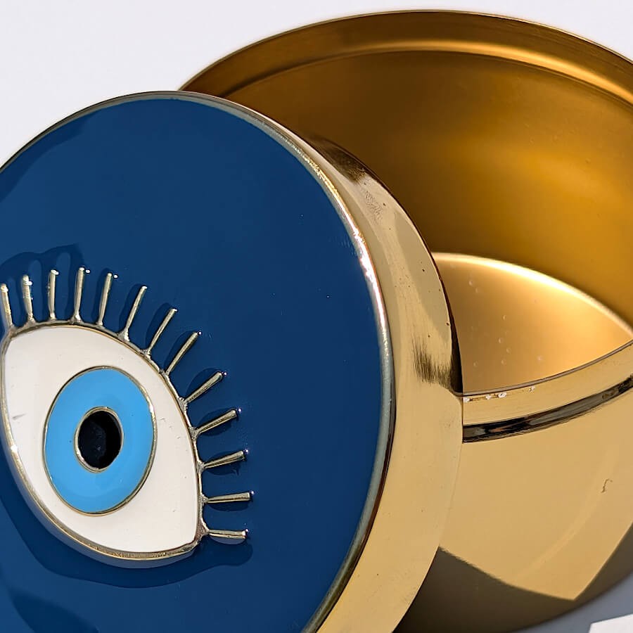 Gros plan sur le couvercle émaillé bleu nuit et cils dorés de la boîte œil protecteur du catalogue Deco-Delight.