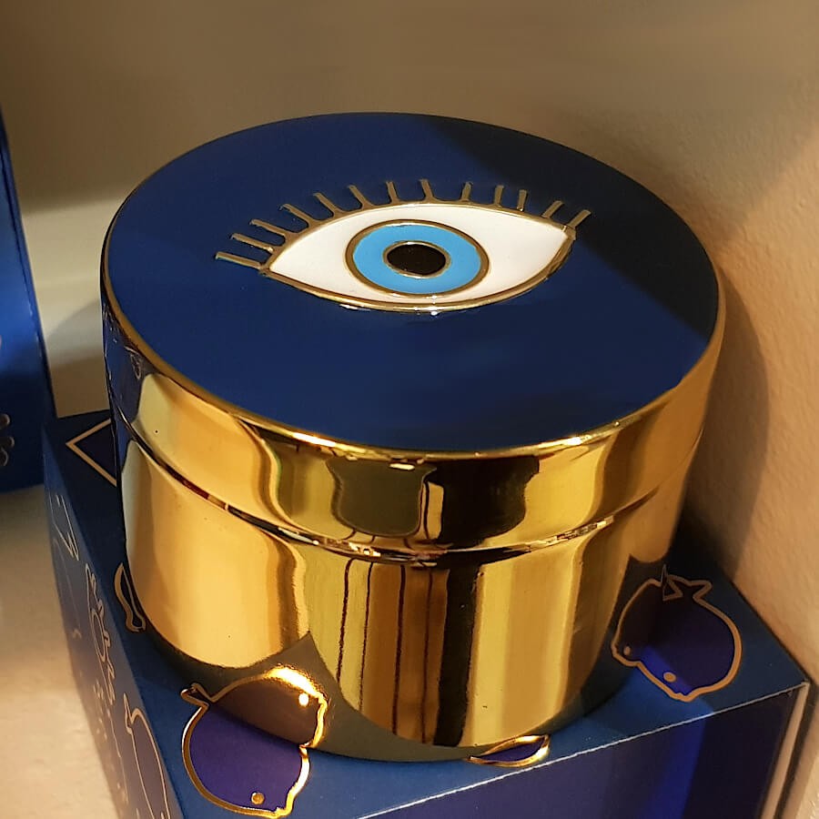 Boîte dorée œil protecteur présentée sur son coffret cadeau bleu nuit.