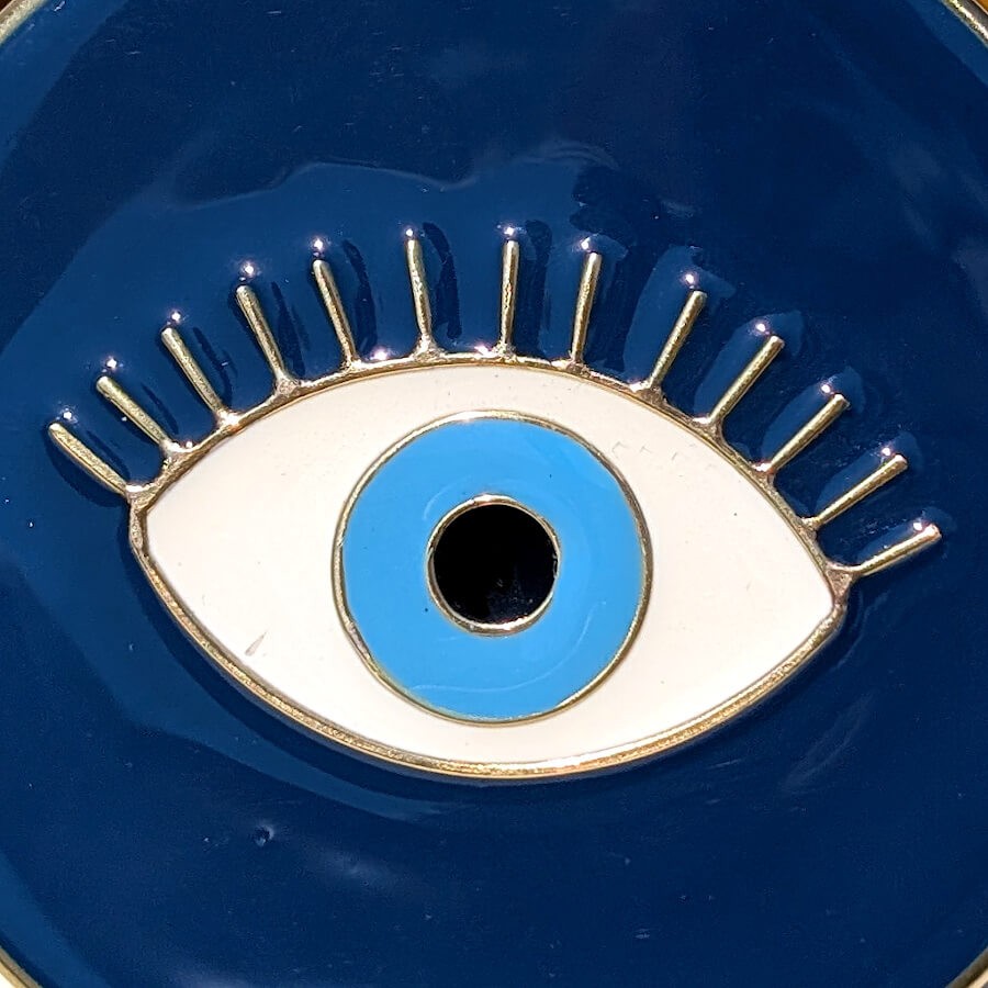 Zoom détaillé sur le travail de l'émail bleu et du métal doré du motif œil protecteur.