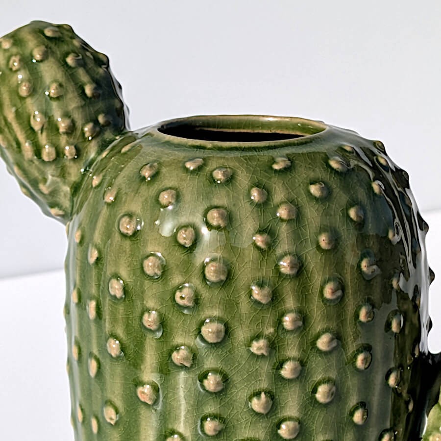 Gros plan sur les reliefs sculptés et la céramique émaillée du vase cactus.