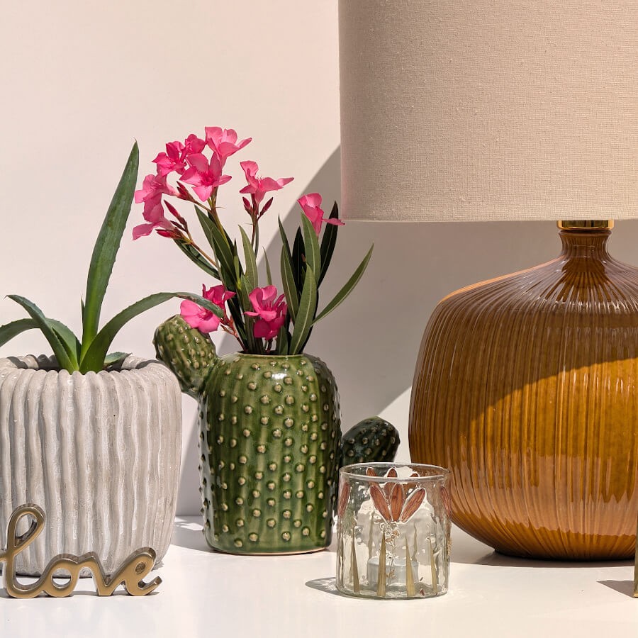 Mise en scène du vase fleuri avec fleurs roses près de la lampe chaleureuse en grès ocre Deco-Delight.