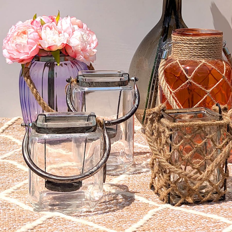 Ambiance champêtre avec le photophore carré et des vases et photophores décoratifs sur un tapis.