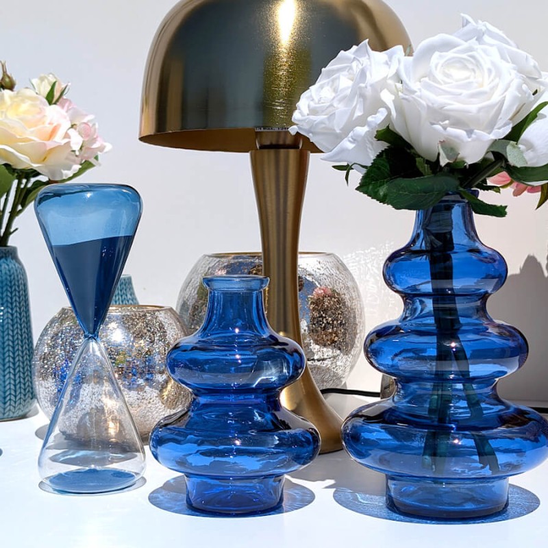 Ensemble d'accessoires décoratifs de salon avec les vases bleus et la lampe champignon dorée.